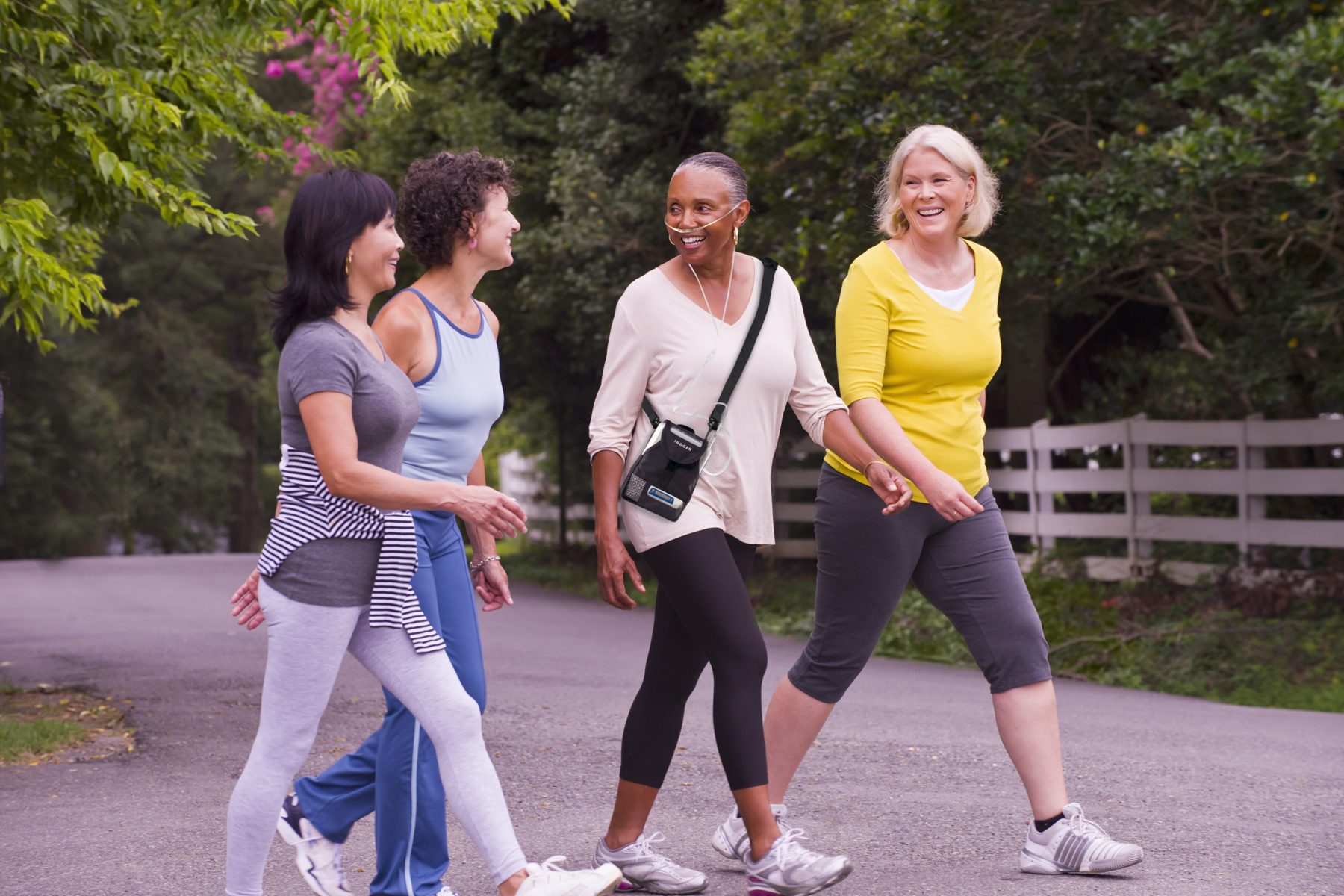 Friends walking together outdoors, one wearing a portable oxygen concentrator